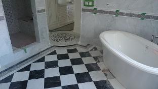 Bathroom under renovation featuring a black-and-white checkered floor, a freestanding white bathtub, and partially tiled walls with a decorative accent stripe.