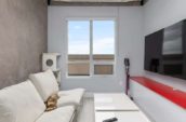Modern minimalist living room with a white sofa, a mounted flat-screen TV, and a coffee table.